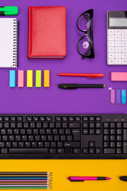 istock Modern working place with keyboard, diary, pencils, pens and glasses on orange-purple background. Top view 1097720086