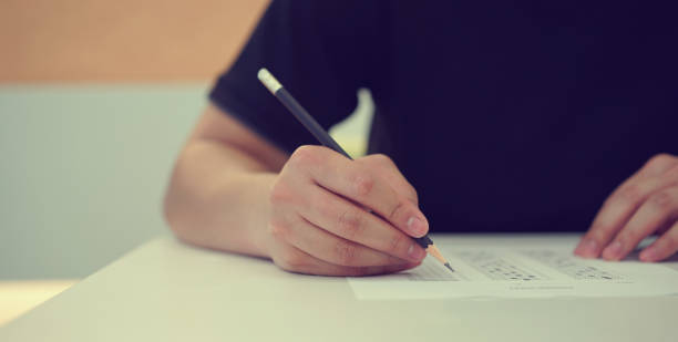istock close up high school student man hand writing by marking choices on answer sheet paper for final examination test in classroom concept 1097722952