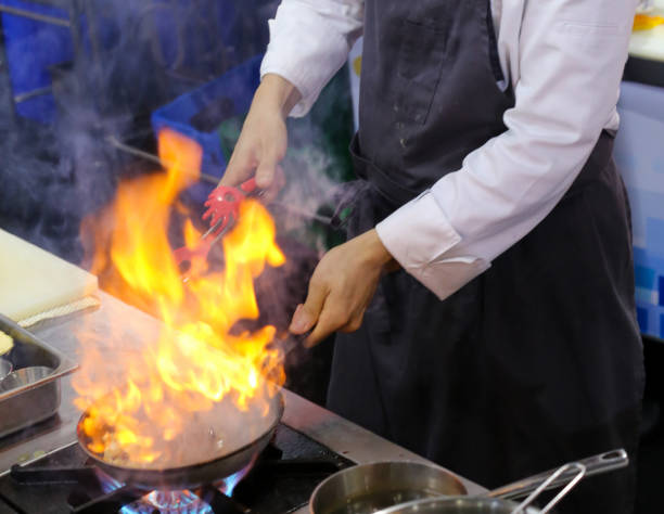 istock Chef in restaurant kitchen at stove with pan, doing flambe on food 1097724766