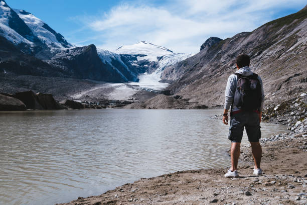 istock Man by lake looking at Alpine glacier 1097726058