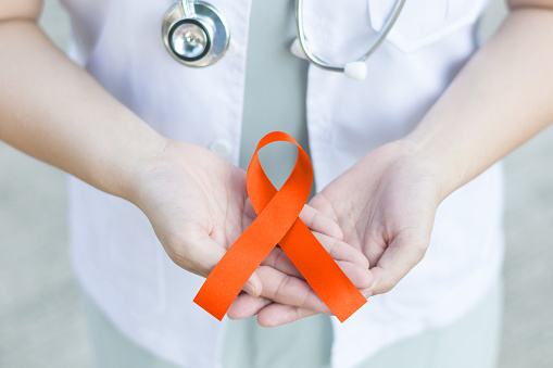 Female doctor in white uniform with orange ribbon awareness in hand as stop sign for ADHD,COPD,Cultural Diversity,Kidney Cancer - Renal Cell Carcinoma,Leukemia, Lupus,Malnutrition,Self Injury,Spinal