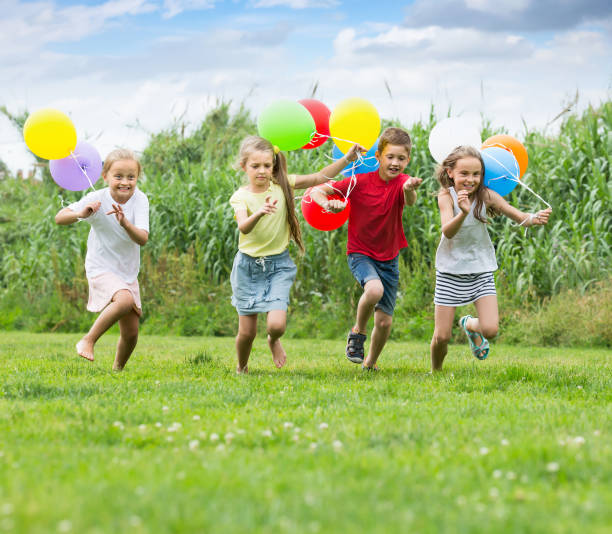 istock Four laughing kids running on green lawn 1097731206