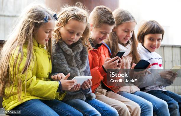 Niños Jugando Con Los Teléfonos Móviles Foto de stock y más banco de imágenes de Niño - Niño, Calle, Dispositivo de información móvil