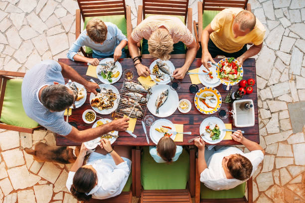 большой семейный ужин miltigeneration в процессе. вертикальный вид сверху на столе с едой и руками - meeting food nature foods and drinks стоковые фото и изображения