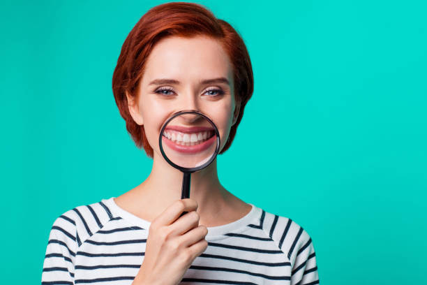 closeup studio photo portrait of charming satisfied cute friendly caucasian teen girl holding transparent magnifier make wide hollywood smile wearing black pullover isolated bright background - gums imagens e fotografias de stock