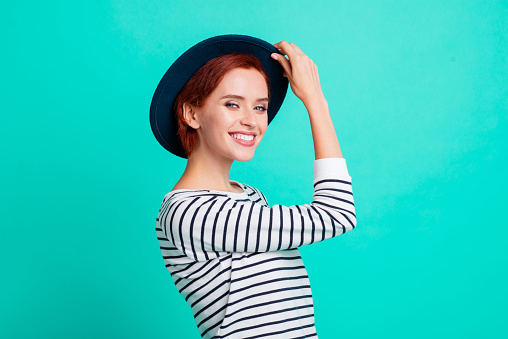 Closeup picture photo portrait of lovely charming stunning confident nice in good mood sweater she her girl holding touching dark blue hat isolated on turquoise background