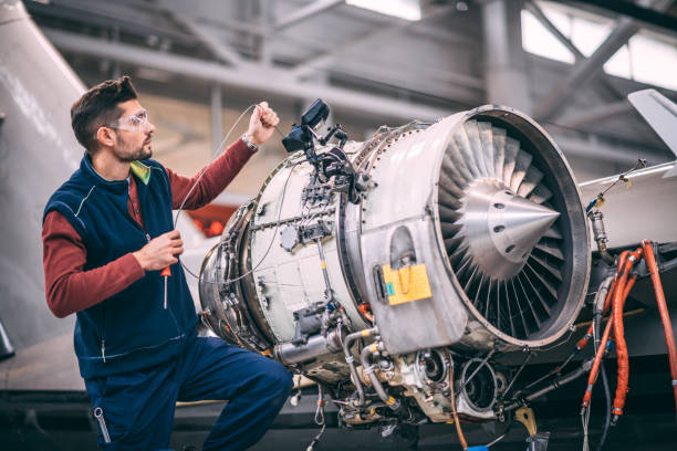 istock Aircraft engineer in a hangar holding a camera probe while repairing and maintaining airplane jet engine 1097755660