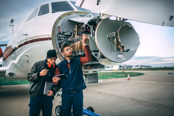 istock Two aircraft engineers fixing a problem on a sensor and radar array in the nose cone of a small private jet parked on an airport field 1097756752