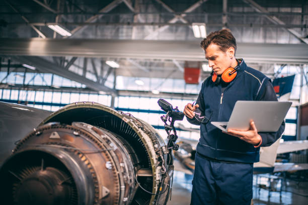istock Aircraft engineer in a hangar holding a laptop computer while repairing and maintaining an airplane jet engine 1097758878