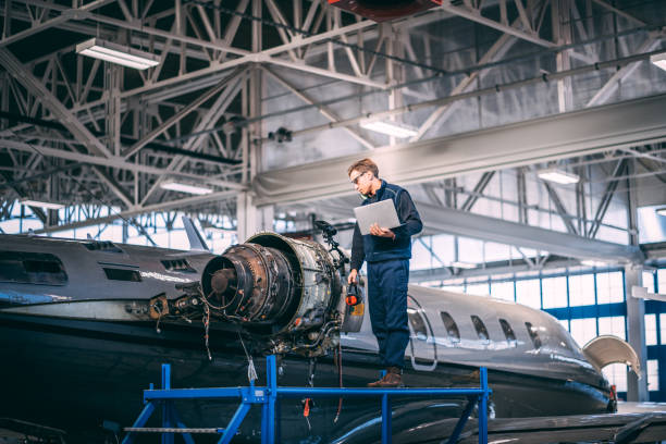 istock Aircraft mechanic standing on a raised work platform, looking at a display of a probe inspection camera, trying to diagnose a fault in a jet engine of a small private airplane in a maintenance hangar 1097759174
