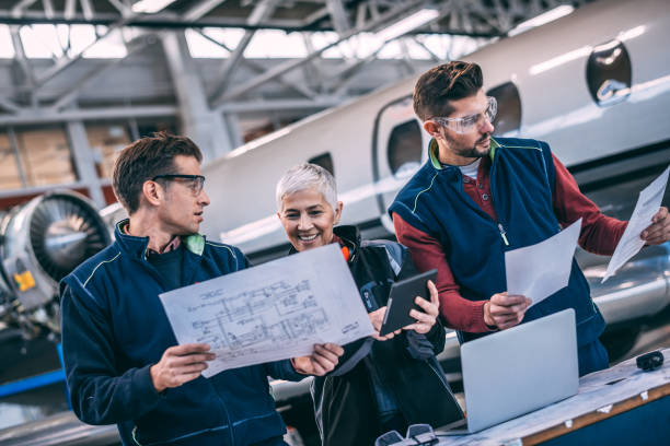 istock Elderly female engineer looking at some blueprints with her crew next to a small private airplane in an aircraft maintenance hangar 1097761608