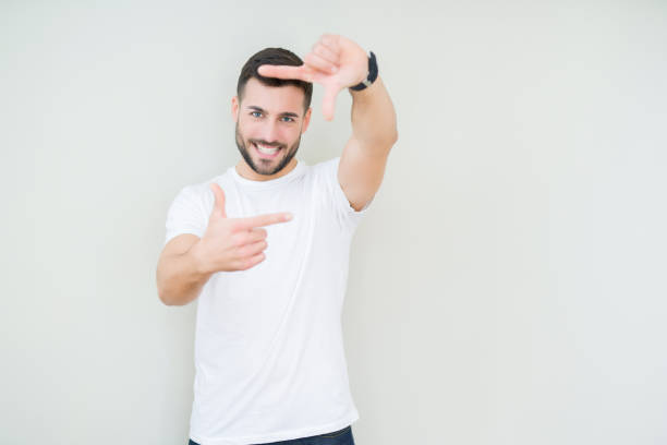 istock Young handsome man wearing casual white t-shirt over isolated background smiling making frame with hands and fingers with happy face. Creativity and photography concept. 1097761976