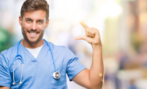 istock Young handsome doctor surgeon man over isolated background smiling and confident gesturing with hand doing size sign with fingers while looking and the camera. Measure concept. 1097766000
