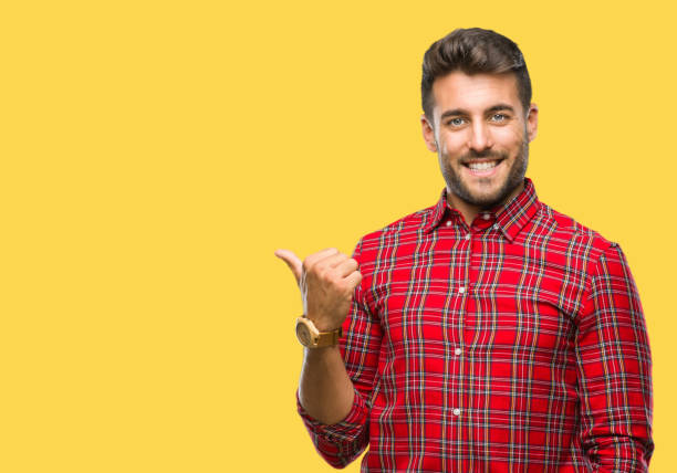 istock Young handsome man over isolated background smiling with happy face looking and pointing to the side with thumb up. 1097766570