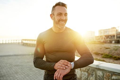 Shot of a man checking his wristwatch while exercising outdoors