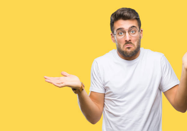 istock Young handsome man wearing glasses over isolated background clueless and confused expression with arms and hands raised. Doubt concept. 1097769066