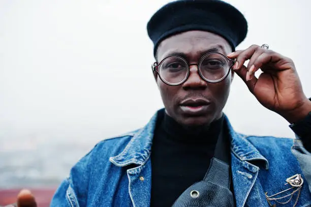 Close up portrait of african american man in jeans jacket, beret and eyeglasses.