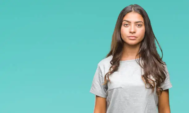 Photo of Young beautiful arab woman over isolated background with serious expression on face. Simple and natural looking at the camera.