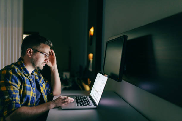 istock Hard working serious young employee with eyeglasses and in shirt using laptop for getting project done while sitting in the office late at night. 1097775244