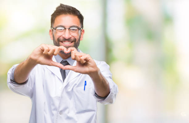 adultos hispanos científico o médico hombre con bata blanca sobre fondo aislado sonriendo en el amor que muestra el símbolo del corazón y forma con las manos. concepto romántico. - made man object fotografías e imágenes de stock