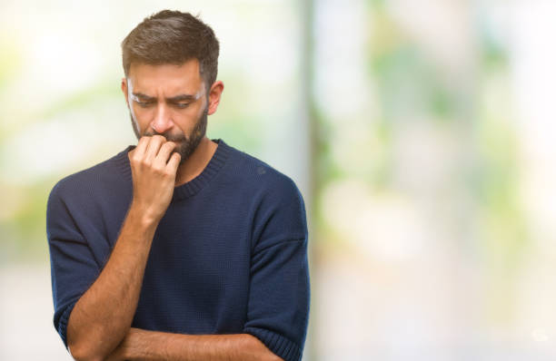 Adult hispanic man over isolated background looking stressed and nervous with hands on mouth biting nails. Anxiety problem. Adult hispanic man over isolated background looking stressed and nervous with hands on mouth biting nails. Anxiety problem. Phobia stock pictures, royalty-free photos & images