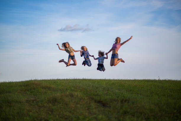 istock Mother and children jumping in meadow 1097783096
