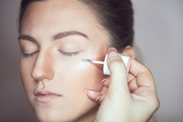 Young beautiful woman applying make-up by make-up artist. Process of making makeup.