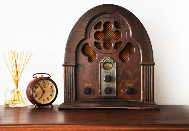 close up view of antique wooden radio and broken clock with white wall in background - radio 1930s imagens e fotografias de stock
