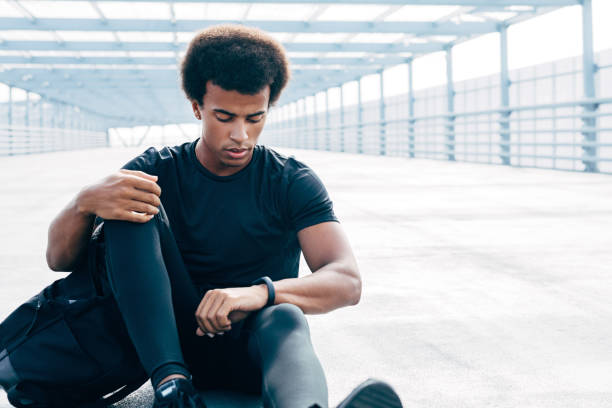istock Male athlete resting after intense training. Sportsman looking at activity tracking device. 1097789436