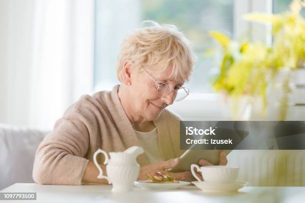 Pleased Senior Woman Using Digital Tablet Stock Photo - Download Image Now - Senior Adult, 70-79 Years, Digital Tablet