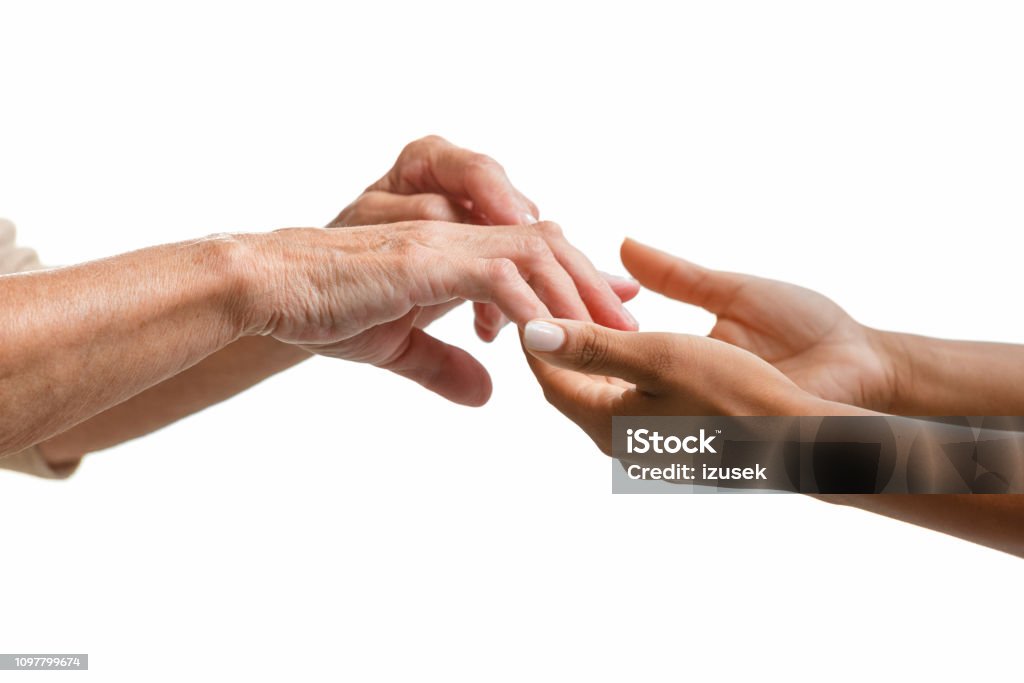 Helping hands Senior and young women hands holding together against white background. Close up, unrecognizable person. Parkinson's Disease Stock Photo