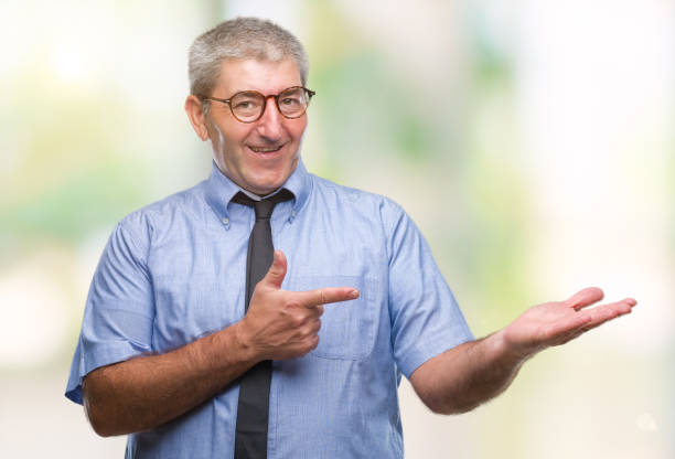 istock Handsome senior business man over isolated background amazed and smiling to the camera while presenting with hand and pointing with finger. 1097800642