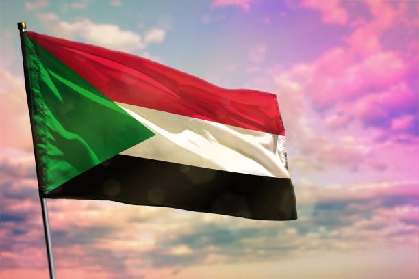istock Fluttering Sudan flag on colorful cloudy sky background. Prosperity concept. 1097800938