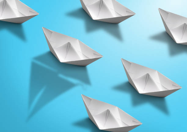 istock stand out concept, paper ship with sailing boat shadow on blue 1097803132