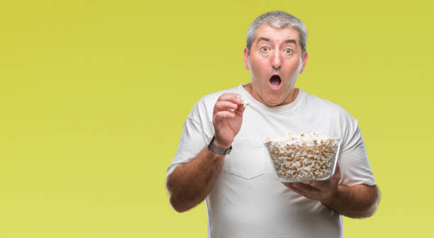 istock Handsome senior man eating popcorn over isolated background scared in shock with a surprise face, afraid and excited with fear expression 1097804000