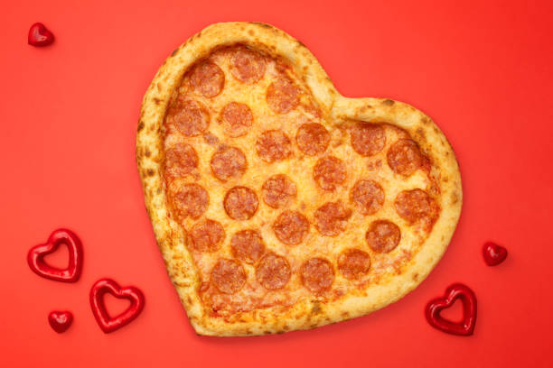 istock Heart shaped pizza pepperoni for Valentines day on red paper background 1097816962