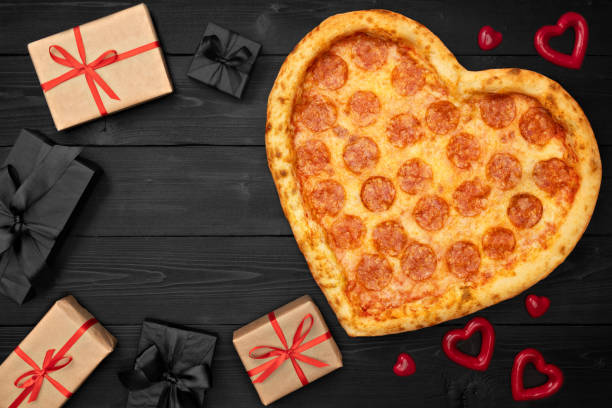 istock Pizza shaped heart with gift box for Valentine's Day romantic concept copy space on rustic dark black background. Top View. Flat lay 1097817540