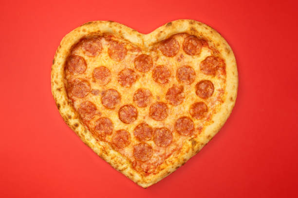 istock Pizza shaped heart top view Valentine's Day on red background 1097817544