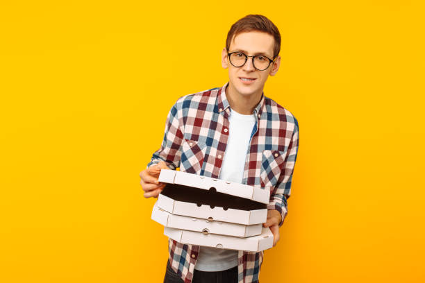 istock man holding a box of pizza on a yellow background 1097822748