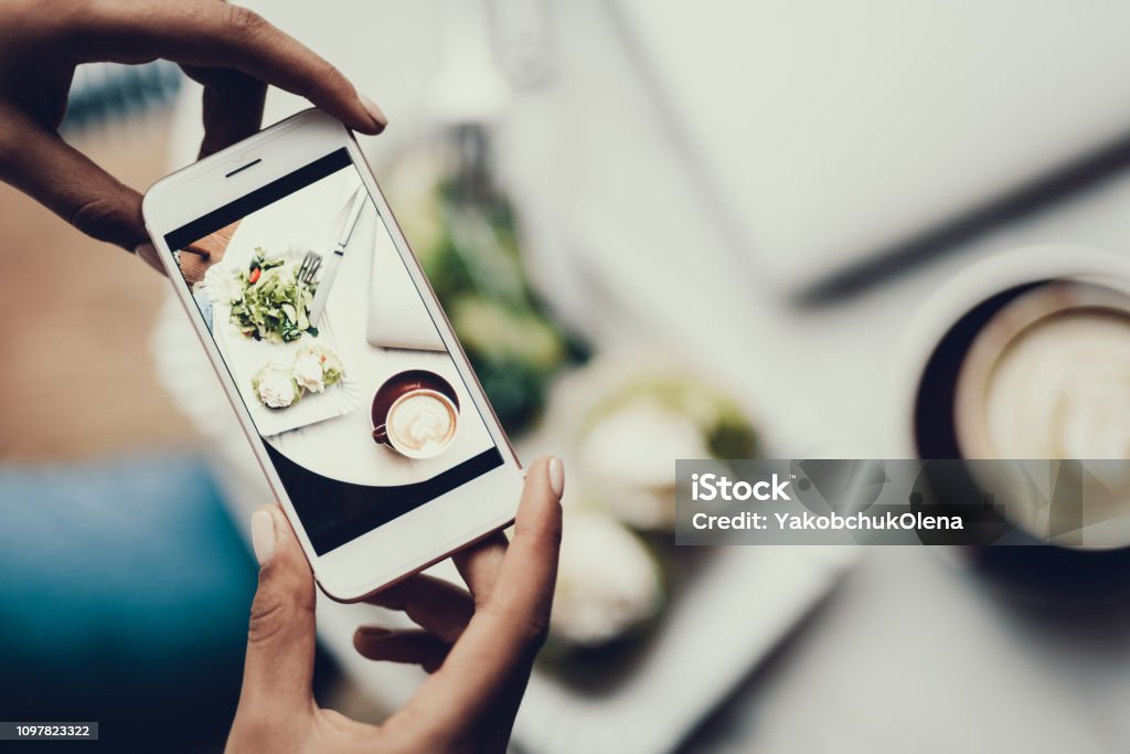 女性の手で彼女の食べ物の写真を撮る携帯電話を保持しています。 - 画像加工フィルタのロイヤリティフリーストックフォト