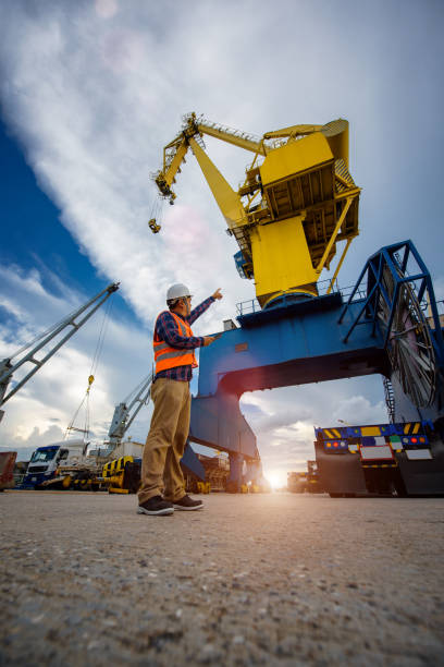 Mission beginning stevedore foreman and or supervisor, loading master takes control in loading discharging operation by walkie talkie and device on line, port operation working under control at quayside gantry crane stock pictures, royalty-free photos & images