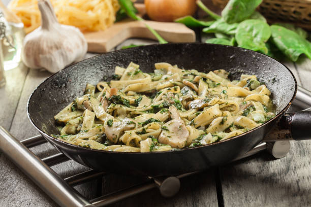 Tagliatelle pasta with spinach and mushrooms on a pan. stock photo