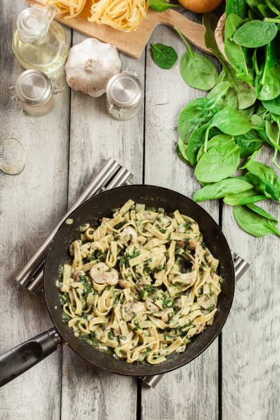 istock Tagliatelle pasta with spinach and mushrooms on a pan. 1097843722