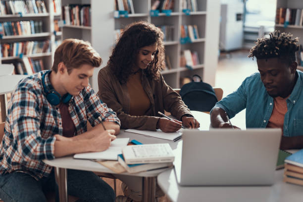 istock Cheerful lady smiling while doing homework with friends 1097847482
