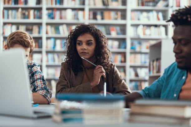 istock Thoughtful student putting pencil to her chin while studying 1097847544