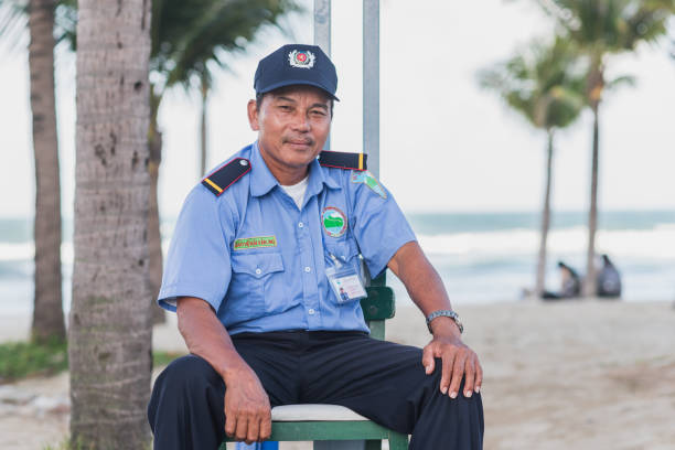 Danang, Vietnam - November 8, 2018: a security guard in uniform poses at his working ground in the seaside street next to Da Nang My Khe beach.