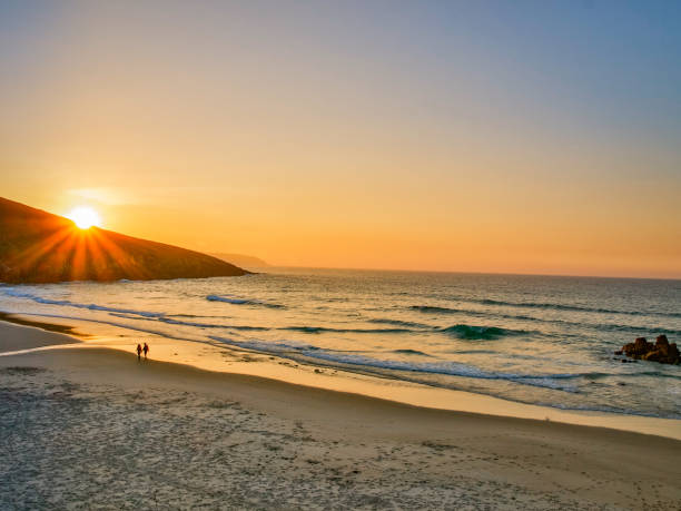 istock Couple walking on the beach in the sunset 1097852320