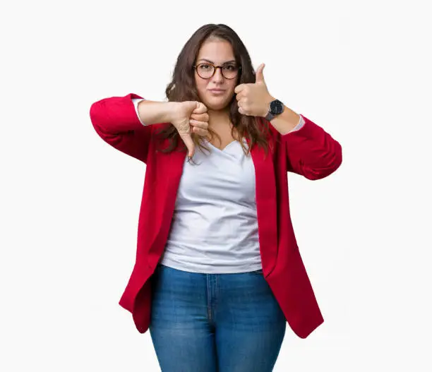 Beautiful plus size young business woman wearing elegant jacket and glasses over isolated background Doing thumbs up and down, disagreement and agreement expression. Crazy conflict
