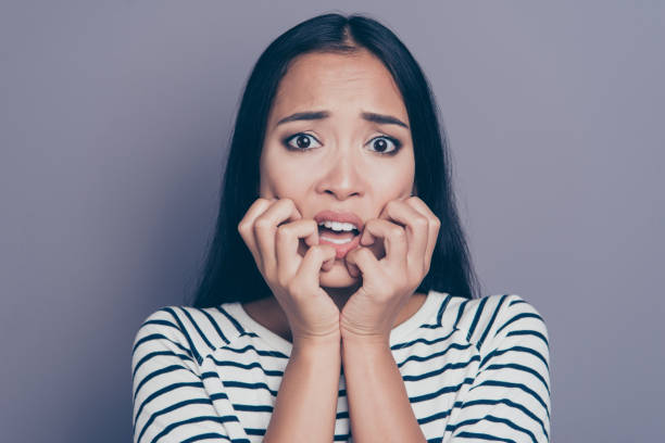 istock Close-up portrait of attractive scared straight-haired lady in striped pullover blouse biting nails grief isolated on gray pastel background 1097854660