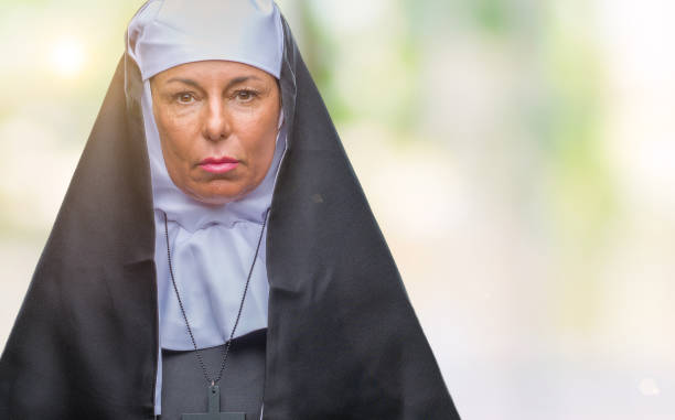 顔に真剣な表情で孤立した背景に中年シニア キリスト教カトリック修道女女。シンプルで自然なカメラを探しています。 - nun catholicism praying women ストックフォトと画像